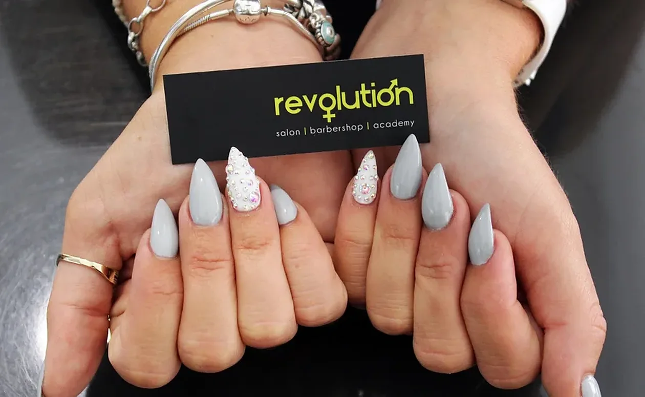 Almond gel nails in soft grey holding a Revolution business card